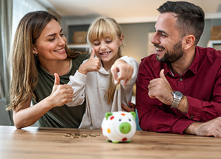 Parents of young girl saving money with piggy bank