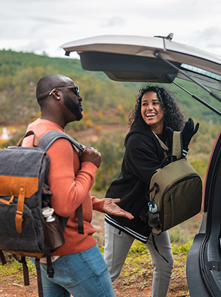 Young couple getting backpacks out of car