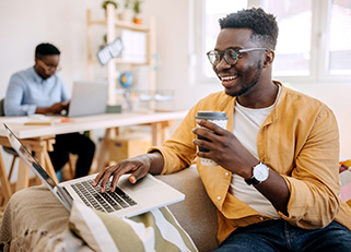 Man drinking coffee while using laptop